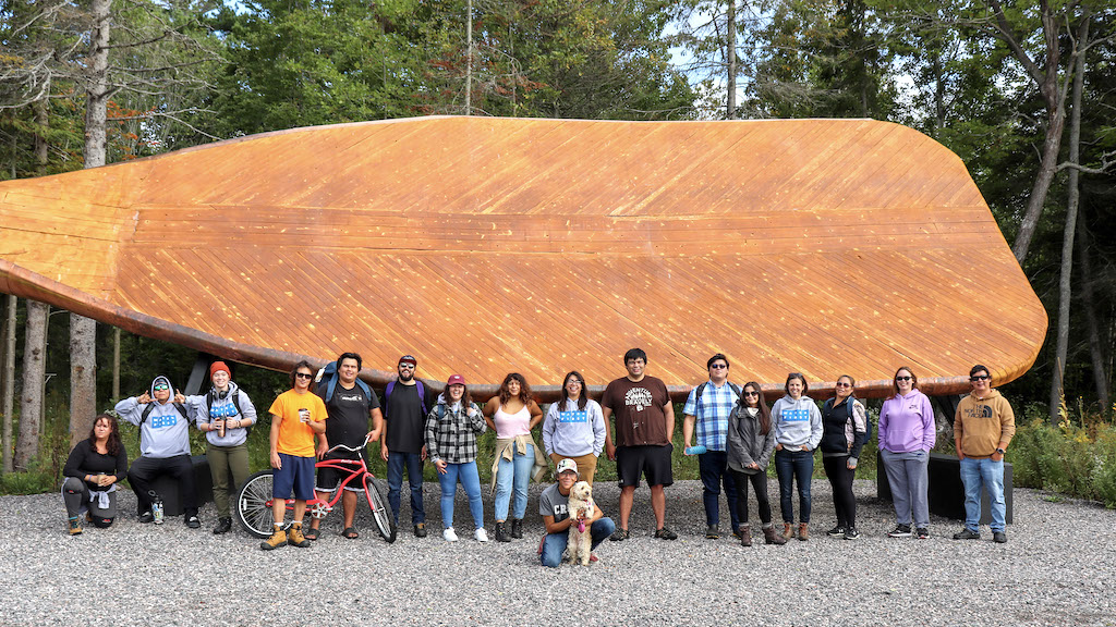 A group of Water First source water quality trainees standing in front of a giant paddle sculpture