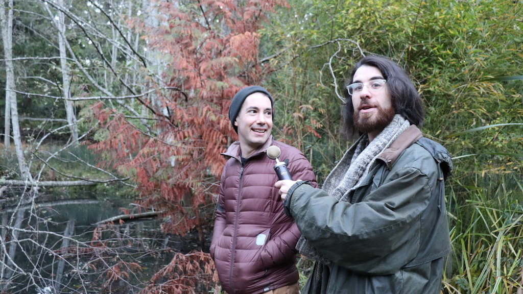 Adam Huggins and Mendel Skulski of Future Ecologies Podcast, standing in the forest with a microphone