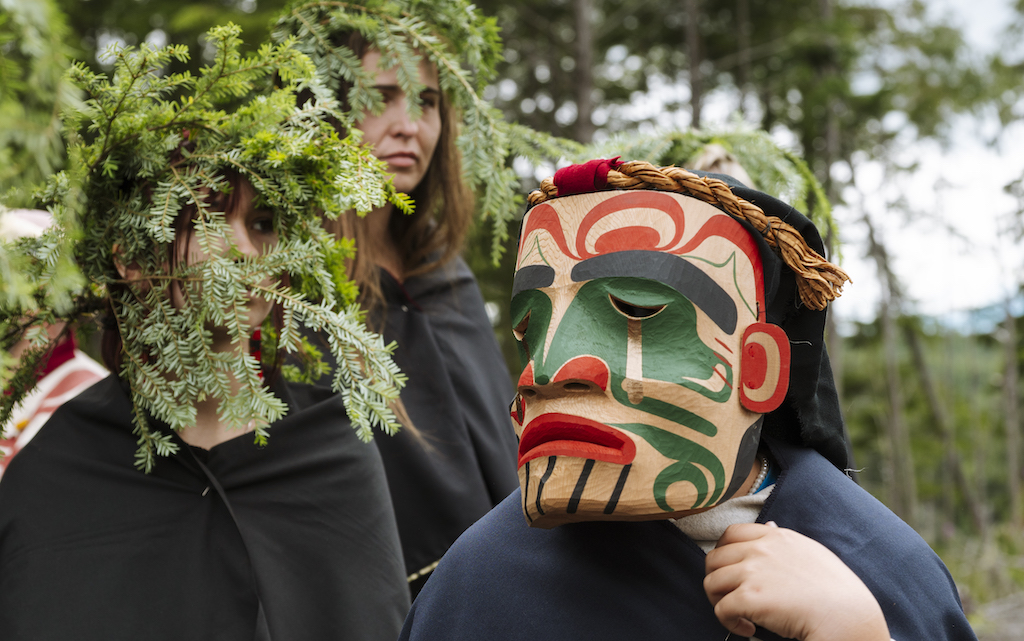 Mourning ceremony, women wearing hemlock boughs, and child wearing carved mourning mask | photo by Agathe Bernard Photography